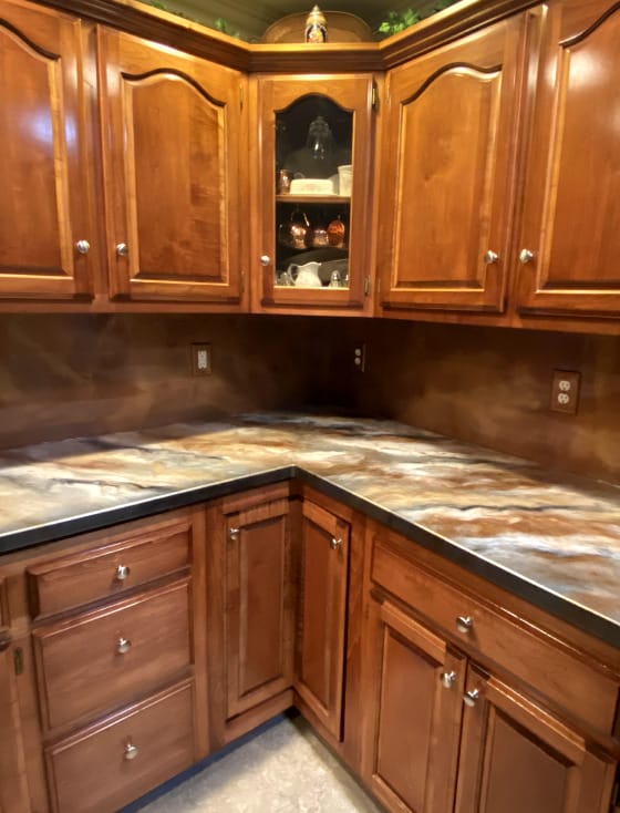 A kitchen with brown cabinets and a marble counter top.