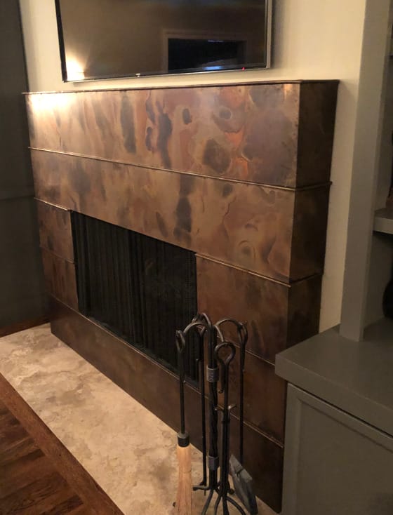 A fireplace with a metal mantle and a tv.